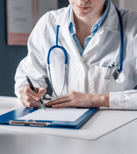 Doctor sitting at desk and writing a prescription for her patient in Peterborough, Ontario, Canada 