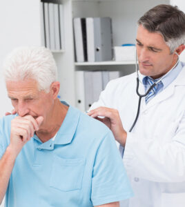 Doctor examining coughing senior patient in clinic in Peterborough, Canada 