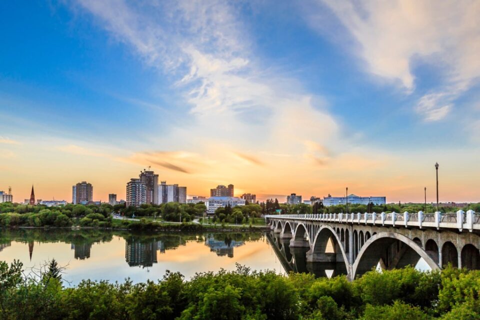 A bridge spans a river with a city skyline visible in the background in Saskatchewan, Canada
